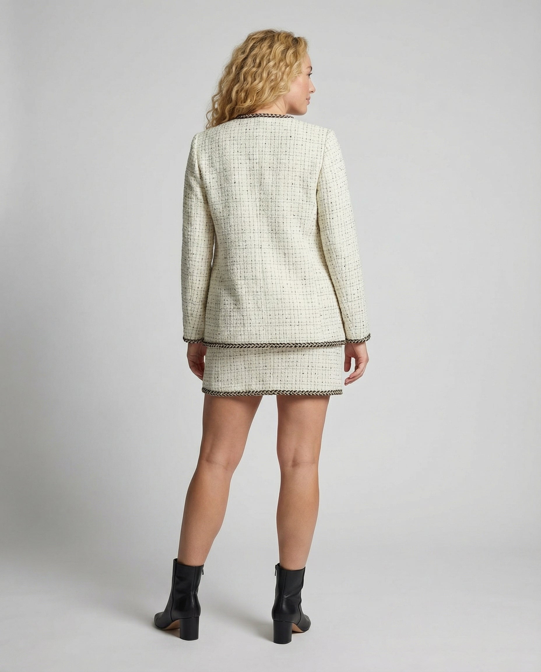 Woman wearing a tweed jacket and skirt set on a plain background