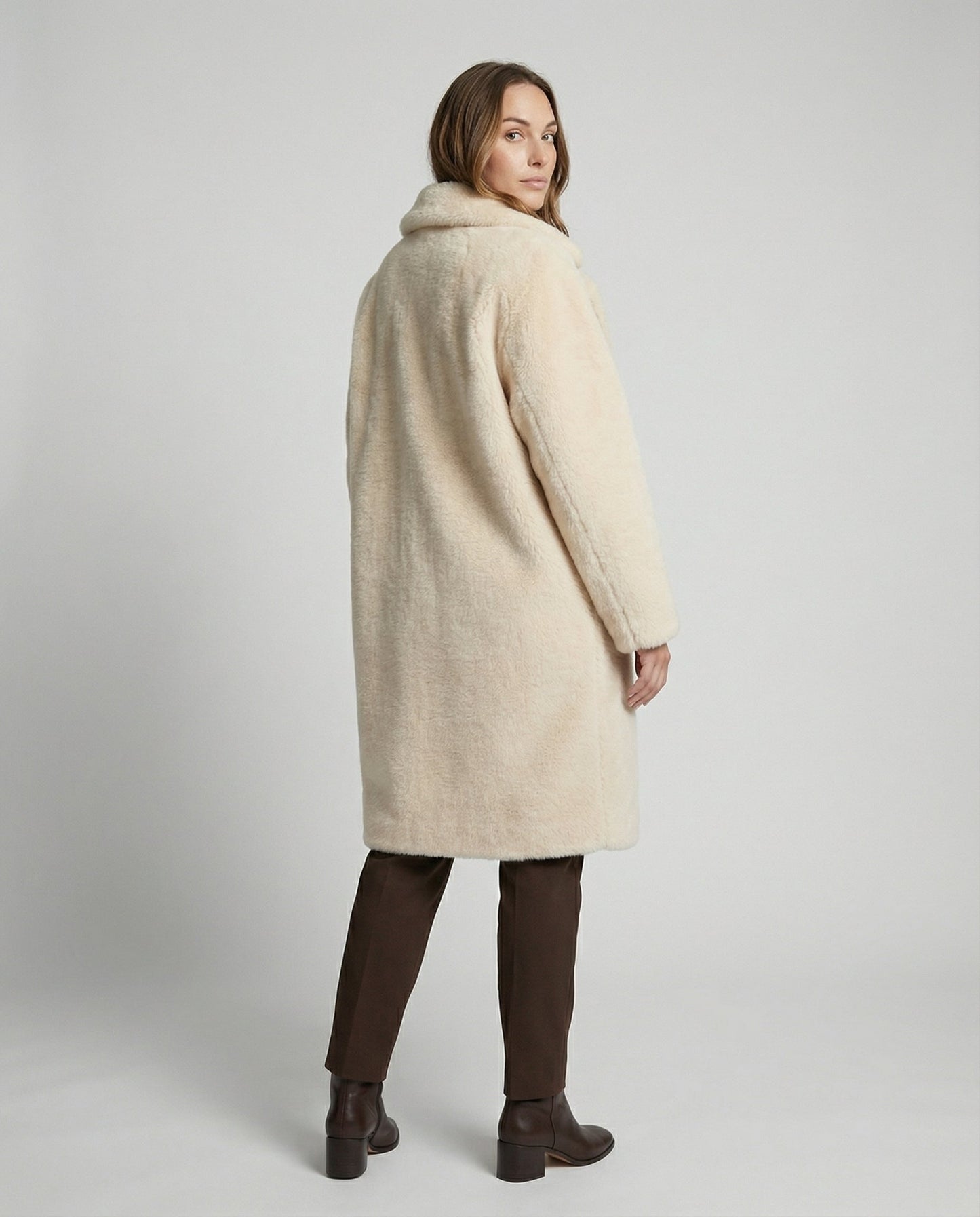 Woman wearing a cream-colored coat on a plain background