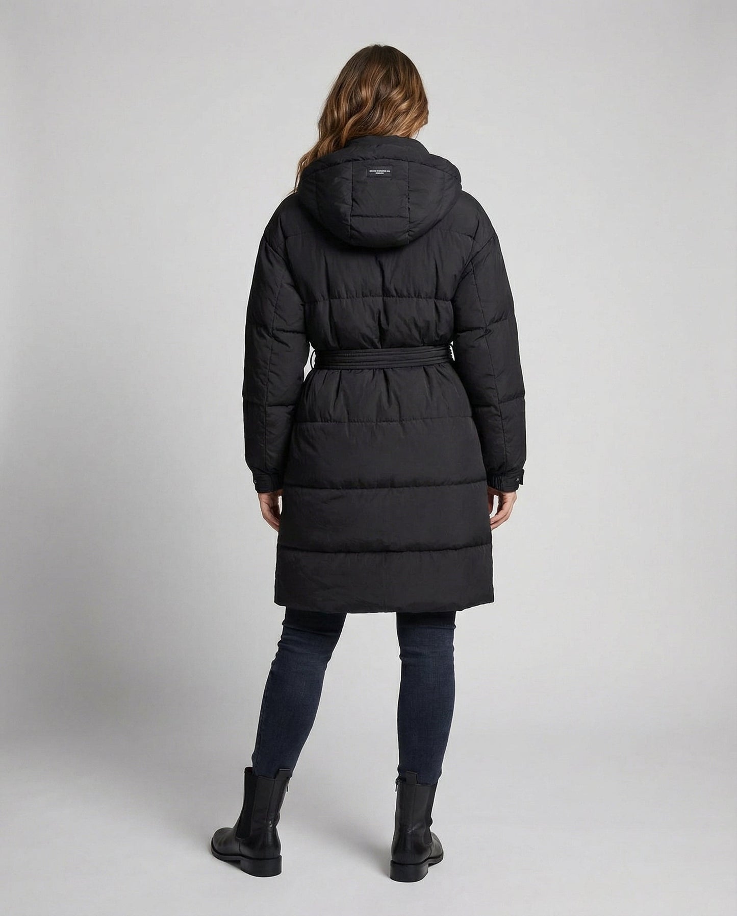 Person wearing a black puffer coat on a light gray background