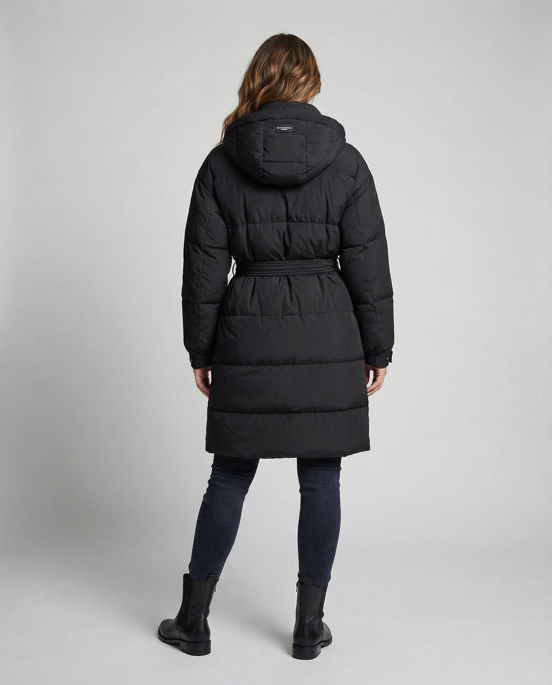 Person wearing a black puffer coat on a light gray background