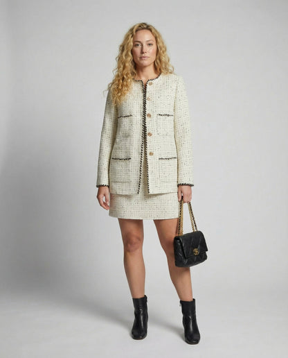 Woman wearing a tweed outfit with a handbag on a plain background