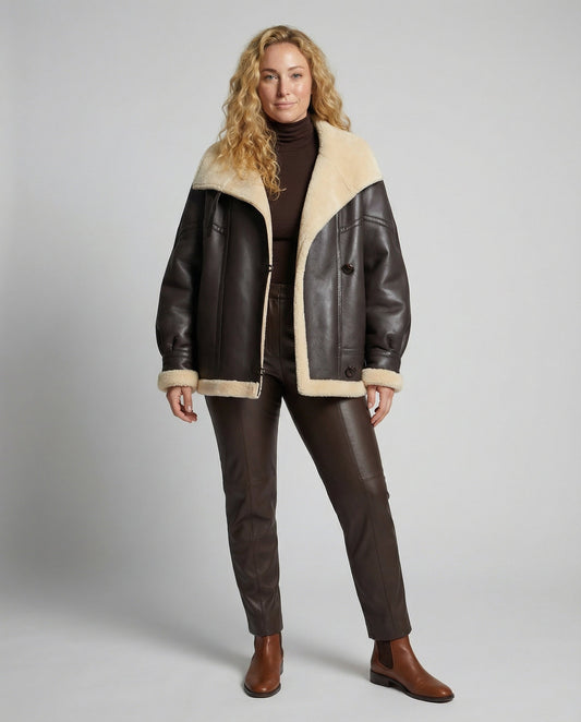 Woman wearing a brown leather jacket with beige fur lining on a gray background