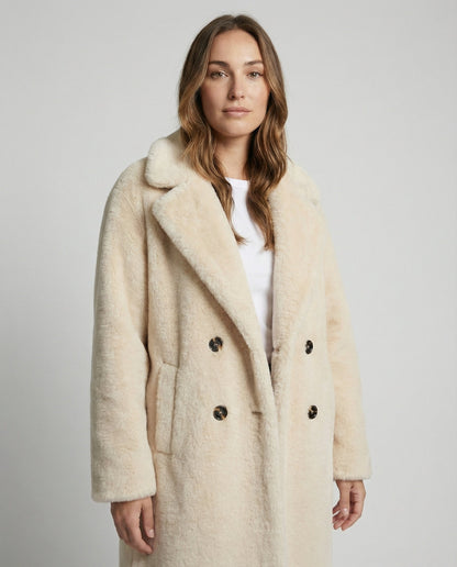 Woman wearing a beige coat against a plain background